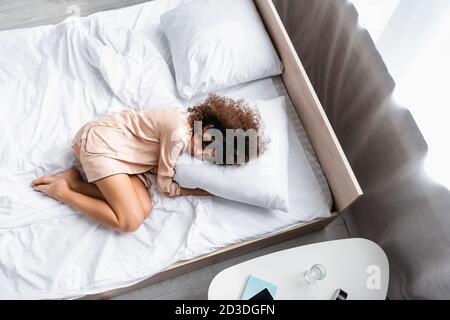 top view of barefoot woman with closed eyes hugging pillow while sleeping on bed Stock Photo Alamy