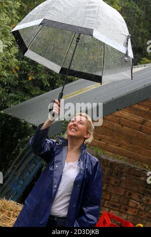 White Caucasian dyed blonde middle aged woman in her 40s wearing a blue  shiny PVC raincoat purchased from a second hand shop. She holds a clear see  through dome umbrella as it rains Stock Photo - Alamy