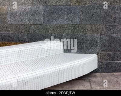 Bench lined with white ceramic tiles on the background of a marble wall Stock Photo