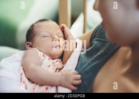 Small caucasian baby sleeping in his mother's hands feeling safe and protected Stock Photo