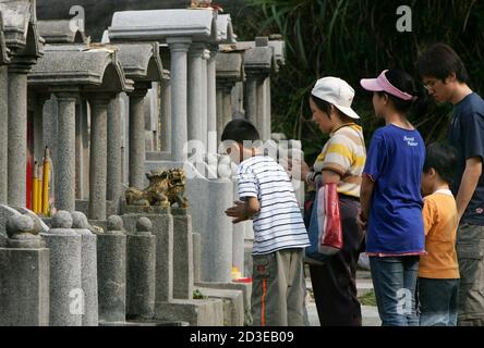 A family honours their ancestors at a cemetery during the Chung Yeung  festival in Hong Kong October 22, 2004. During the festival, many people  visit the graves of family members to perform cleansing rites and pay their  respects. REUTERS/Kin Cheung KC ...