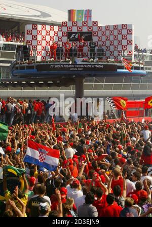 Ferrari's fans celebrate Brazilian Ferrari driver Rubens Barrichello victory, second placed German teammate World champion Michael Schumacher and third place Irish Jaguar driver Eddie Irvine on podium at the end of the Italian GP at Monza track September 15, 2002. Brazilian Rubens Barrichello led Michael Schumacher to a runaway one-two win before a red sea of Ferrari fans in their home Italian Grand  Prix on Sunday.