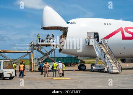 A Boeing B747 Jumbo Jet freighter aircraft with a wide open nose cargo door being offloaded by a high-loader at a cargo ramp Stock Photo