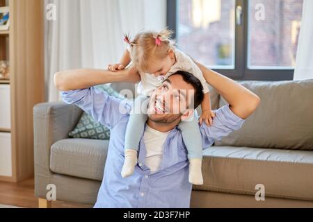 father riding little baby daughter on neck at home Stock Photo