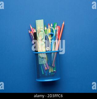 plastic scissors and multicolored wooden pencils on a blue background, flat lay, copy space Stock Photo