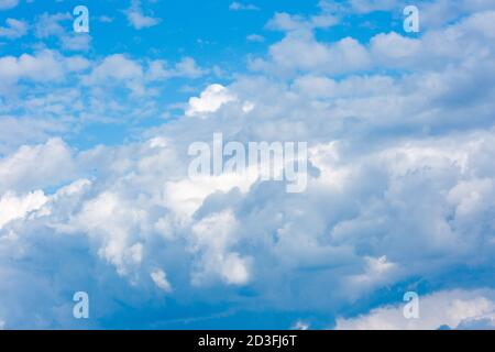 Large clouds and storm clouds close-up against a blue sky. White clouds are mixed with thunderclouds. Stock Photo