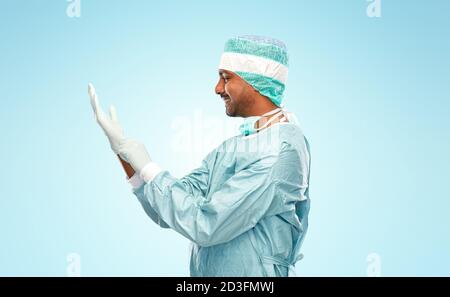 indian male doctor or surgeon putting glove on Stock Photo