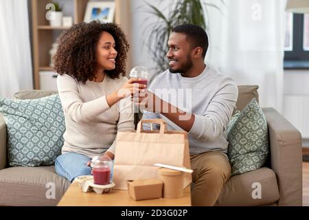 happy couple with takeaway food and drinks at home Stock Photo