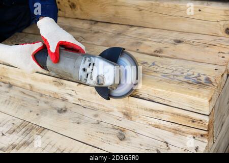 A carpenter worker is grinding a wooden surface with an electric sander. Stock Photo