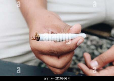 Man hand makes a cigarette with rolling traditional tools, hands closeup. Stock Photo