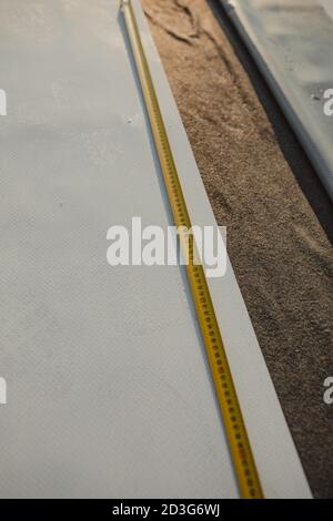 Tape measure unfolded on amembrane roof. Stock Photo