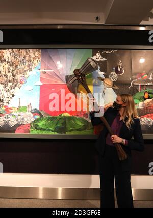 Gallery Assistant Laurel Kemp posing with a Stormbreaker axe prop used by Thor in Avengers: Infinity War priced at £15,000 - £20,000, next to an artwork by Coldplay and Pilar Zeta for the band's 2015 album A Head Full of Dreams, priced at £20,000 - £30,000, which are part of Bonhams’ forthcoming Entertainment Memorabilia sale on the 13th of October. Stock Photo