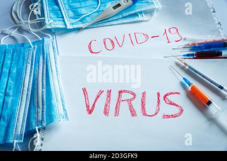 Syringes with colored liquid inside and the name of the COVID-19 virus as the concept of a vaccine against the virus during a pandemic. Stock Photo
