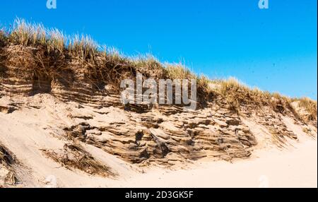 Close up of battered sand dunes on Montauk Beach New York with a deep blue sky above taken in April 2020. Stock Photo