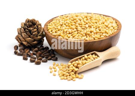 Peeled pine nuts in a wooden bowl and ripe pine cone isolated on a white background. Close-up and full depth of field. Stock Photo