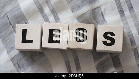 Less word on wooden cubic blocks with letters. Spend less or cut costs business concept Stock Photo