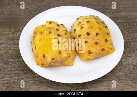 Peeled pineapple and cut in half in a plate, Tasty and juicy pineapple, Benefits of pineapples. Wooden Background Stock Photo