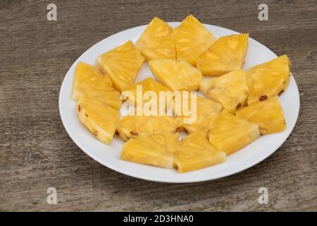 Slices of pineapple on a plate, The benefits of pineapple, Wooden Background Stock Photo