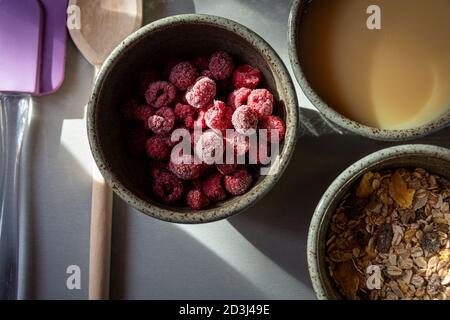 cerial bar ingredients in ceramic bowls top view ,condensed milk ,mueseli  and rasperrys. Stock Photo