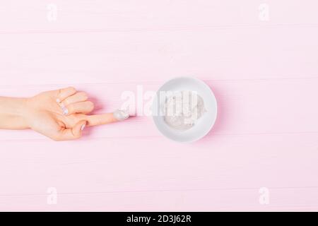 Woman's hand takes freshly made homemade clay face mask, top view. Stock Photo