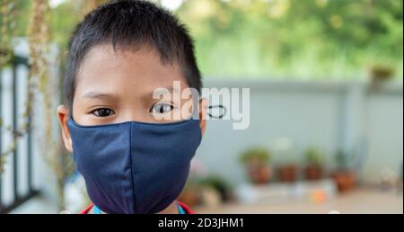Close-up portrait of a cute boy wearing a protective mask and he is looking at the camera. Stock Photo
