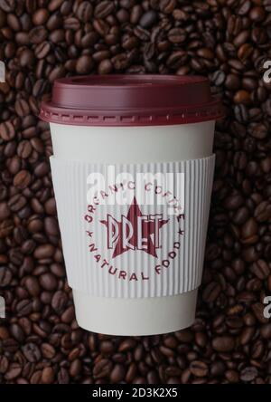 LONDON, UK - SEPTEMBER 09, 2020: Paper cup for takeaway of Pret a Manger coffee on top of fresh raw coffee beans. Stock Photo
