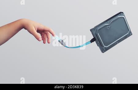 Hand of a child, touching hard disk with a cable; creative technology and future concept, with copy space Stock Photo
