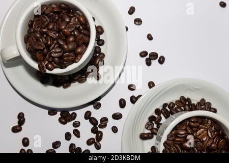 Coffee beans in two coffee cups , on white isolated background.Top view.Creative background. Stock Photo