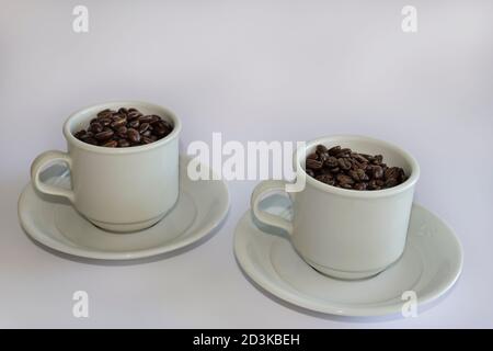 Coffee beans in two coffee cups , on white isolated background. Stock Photo