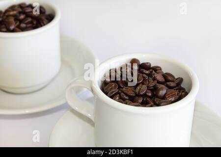 Coffee beans in two coffee cups , on white isolated background.Closeup view. Stock Photo