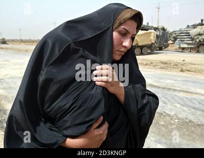 An Iraqi woman, a refugee from the Baghdad area, covers her baby against the heat on the road south-east of Baghdad on April 5, 2003. U.S. tanks which pushed into southern Baghdad on Saturday rumbled back down the main southern highway from the city after linking up with U.S. forces at the airport and carrying out a reconnaissance mission.  PP03040014   REUTERS/Oleg Popov