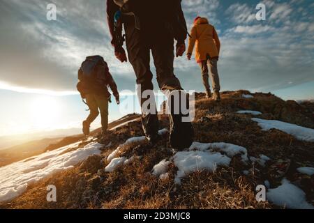 Small group of tourists walks at mountain top at sunset time. Close up photo
