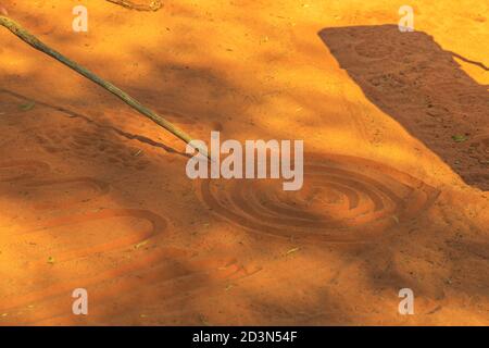 Kings Creek Station, Northern Territory, Australia - Aug 21, 2019: aboriginal people creating shapes with red sand on the ground in aboriginal art Stock Photo