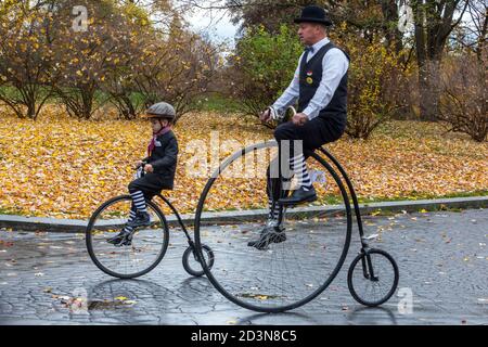 Man riding a penny farthing bicycle at a family festival in summer