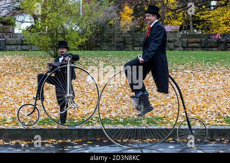 Two cyclists on Penny Farthing bicycles costumes, wearing tail coat Stock Photo