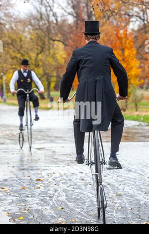 Two cyclists on Penny Farthing bicycle historical clothing wearing tail coat Stock Photo