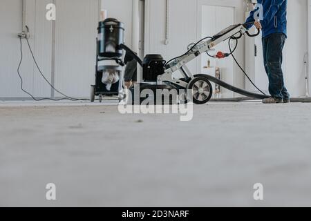 Construction worker using machine polishing surface floor smoothing and finishing hardener or epoxy concrete in the factory. Stock Photo