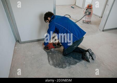 Construction worker using machine polishing surface floor smoothing and finishing hardener or epoxy concrete in the factory. Stock Photo