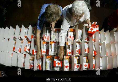 Volunteers place Canadian flags in lunch boxes, in Vancouver June 30, 2003, while preparing for the upcoming 2010 Olympic Bid annoucement. The boxes will be handed out to 18,000 people who will gather in GM Place to watch the announcement from Prague on July 2. Vancouver is competing with Salzburg, Austria and Pyeongchang, South Korea to host the 2010 Winter Olympics. REUTERS/Andy Clark  AC/GAC