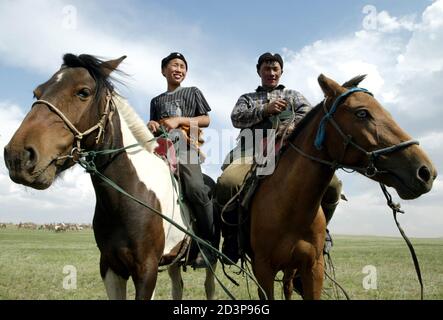 Mongolian nomads mount their horses at Khui Doloon Khudag village, some 35 km (21 miles) from the capital Ulan Bator July 10, 2003 on the eve of the Naadam Festival. Naadam is the biggest event on the Mongolian calendar held from July 11 to 13, on the anniversary of the Mongolian revolution of 1921. [Concerts, fairs and traditional sports like wrestling, archery and horse racing are held during the celebration.]