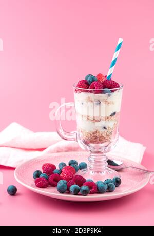 Beautiful dessert with cream and strawberries, raspberries, blueberries on a soft pink background. Stock Photo