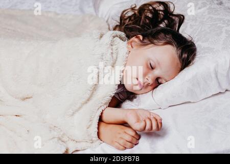a five-year-old girl sleeps peacefully on an orthopedic pillow, home comfort and warmth, healthy sleep Stock Photo