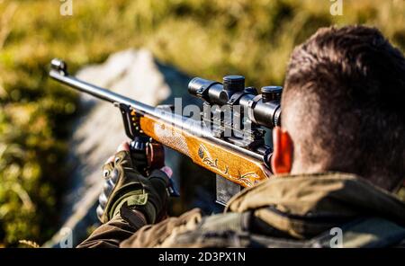 Hunter with hunting gun and hunting form to hunt. Hunter is aiming Stock Photo