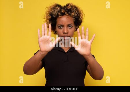 Young african woman makes a gesture stop, on a yellow background Stock Photo