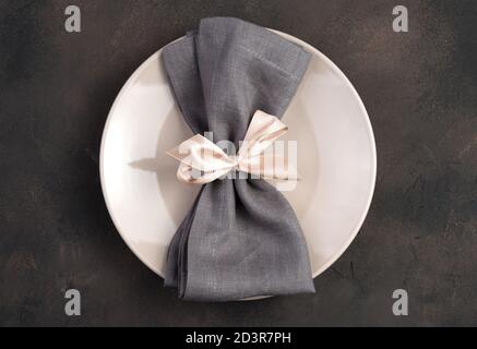 Plate decorated with a gray napkin with a pink ribbon. Stock Photo