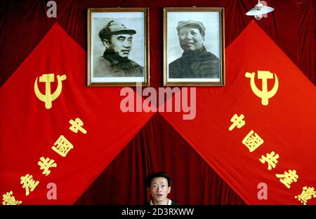 A Chinese man stands underneath portraits of the late chairman Mao Zedong (R) and the late general Zhu De at an exhibition in Beijing June 15, 2004. The exhibition is aimed to promote China's Communist Party which celebrates its 83rd anniversary on July 1. The Chinese characters on the flags read: 'China's Communist Party'. REUTERS/Guang Niu  ASW/LA