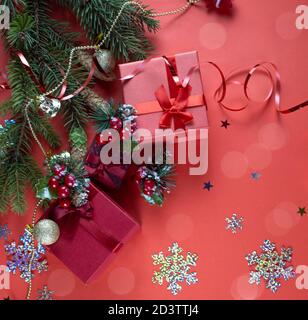 Christmas red gift box with a red bow on a red background. Spruce branch with red berries. Copyspace Stock Photo