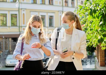 Office workers two women walking, wearing medical protective masks
