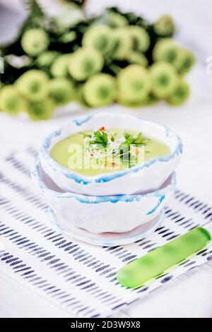 Homemade cream soup with green peas, parsley leaves and alfalfa sprouts on a white background Stock Photo