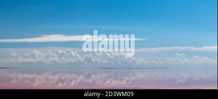 Pink salt lake water surface with mirror reflection of magic clouds with blue sky panorama. Syvash or Sivash, the Putrid Sea or Rotten Sea, Ukraine Stock Photo